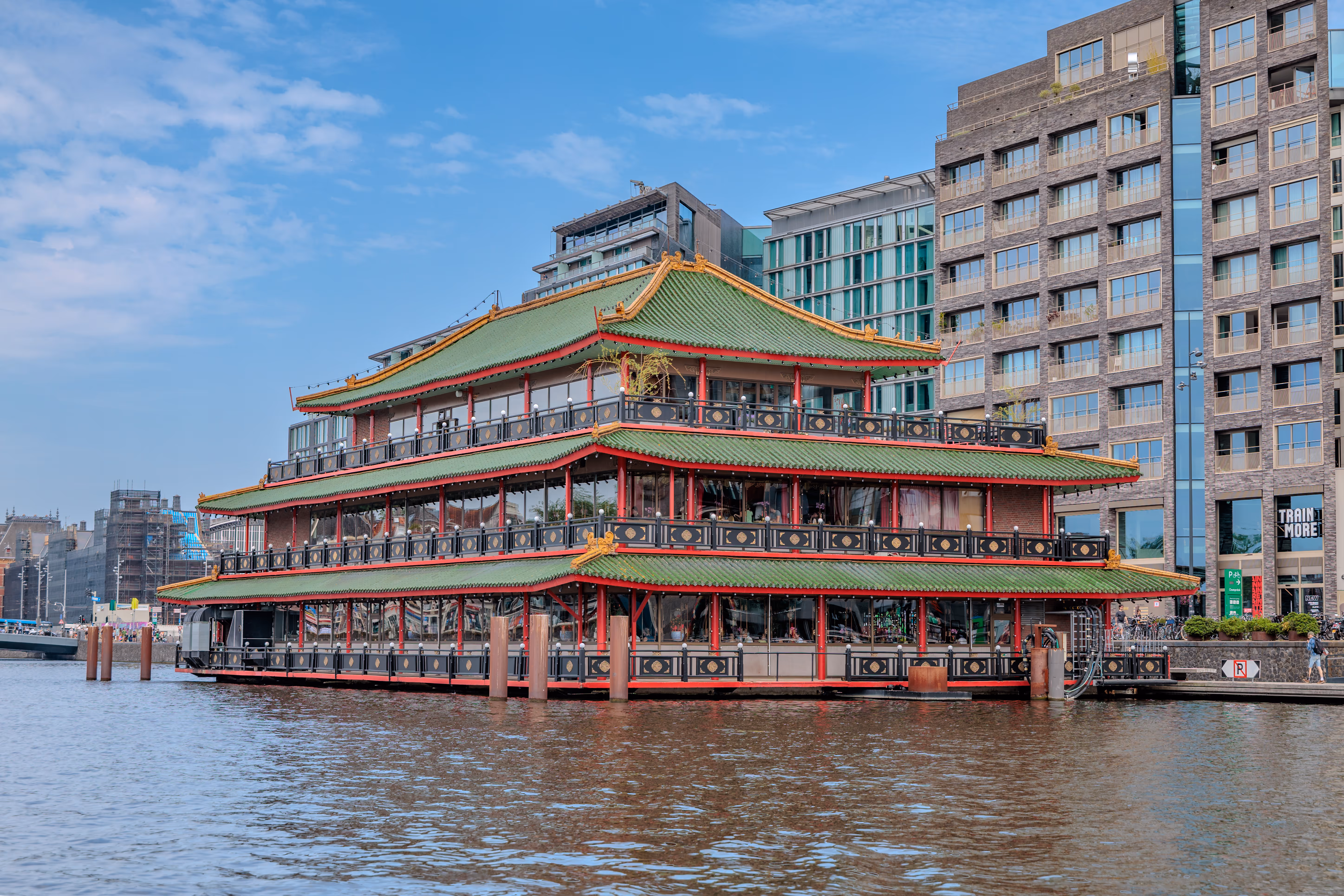 Ein prächtiges chinesisches Schwimmrestaurant mit grünem Pagodendach liegt malerisch auf einem Kanal in Amsterdam, umgeben von städtischen Gebäuden - 2025/06/14