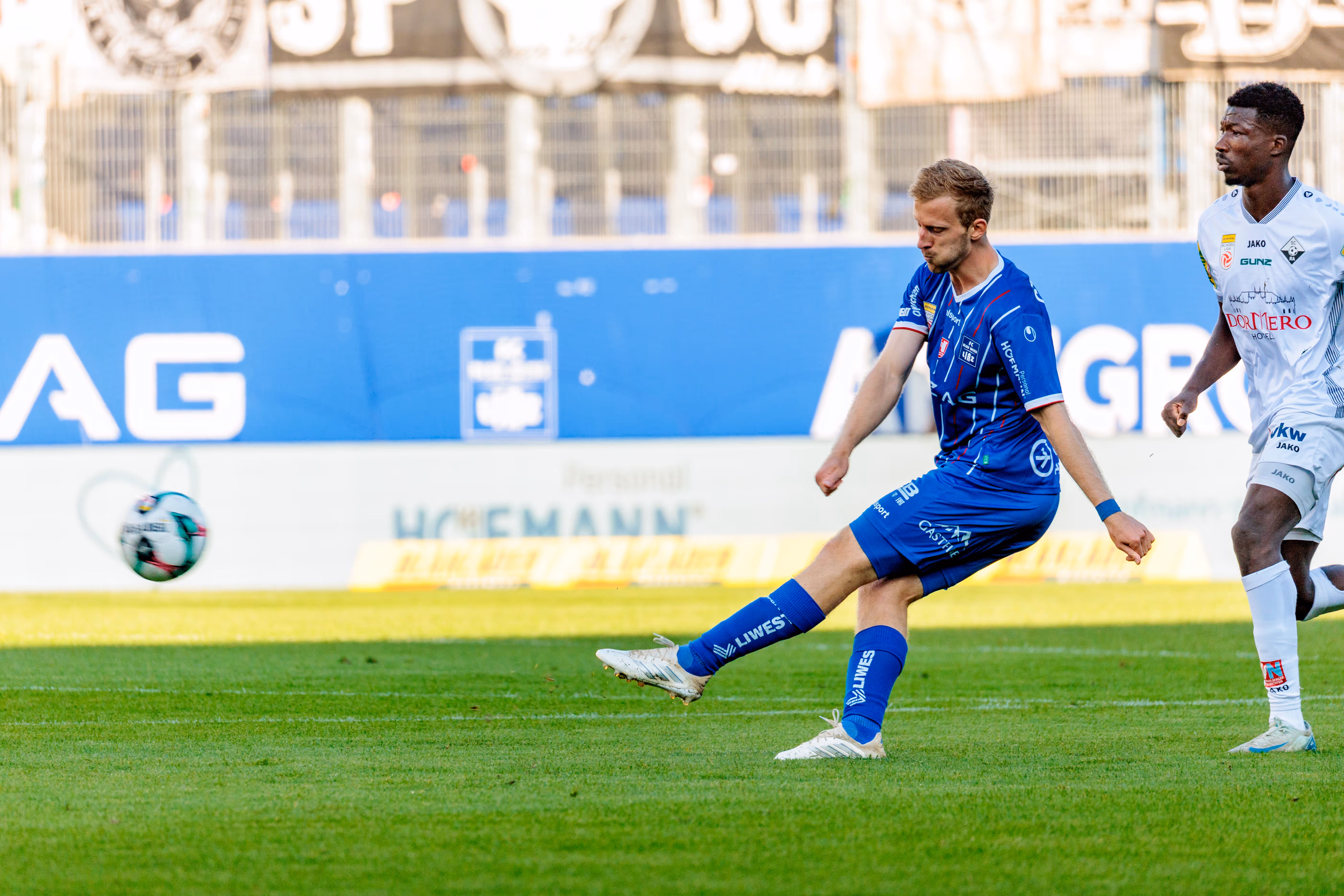 Thomas Goiginger vom FC Blau-Weiß Linz bei einem kraftvollen Flanke im Bundesligaspiel gegen den SCR Altach, während ein Gegenspieler die Szene beobachtet