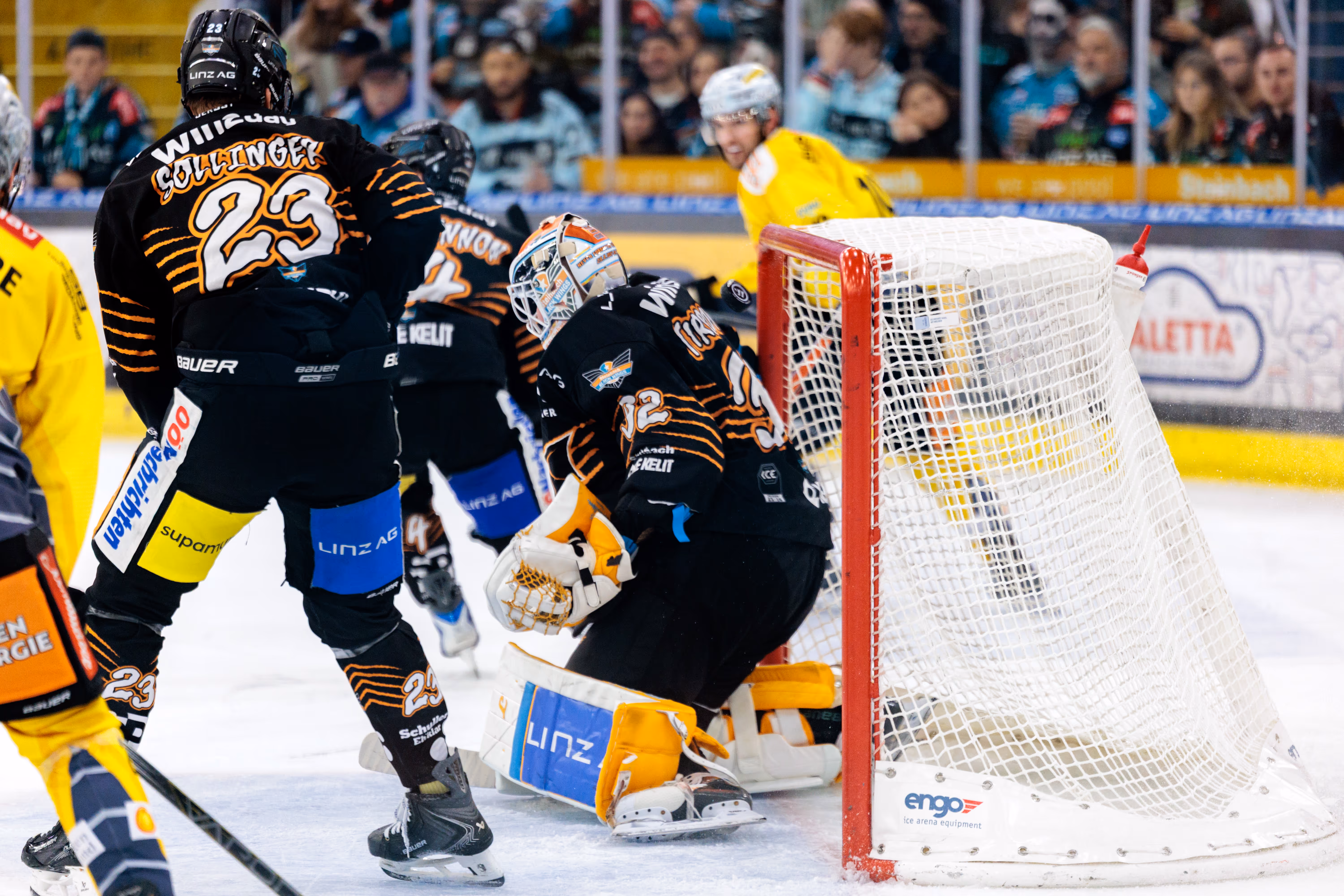 Der Torhüter der Black Wings Linz, Rasmus Tirronen, verteidigt in einer intensiven Spielszene sein Tor. Der Puck befindet sich zwischen Tirronen und Tor