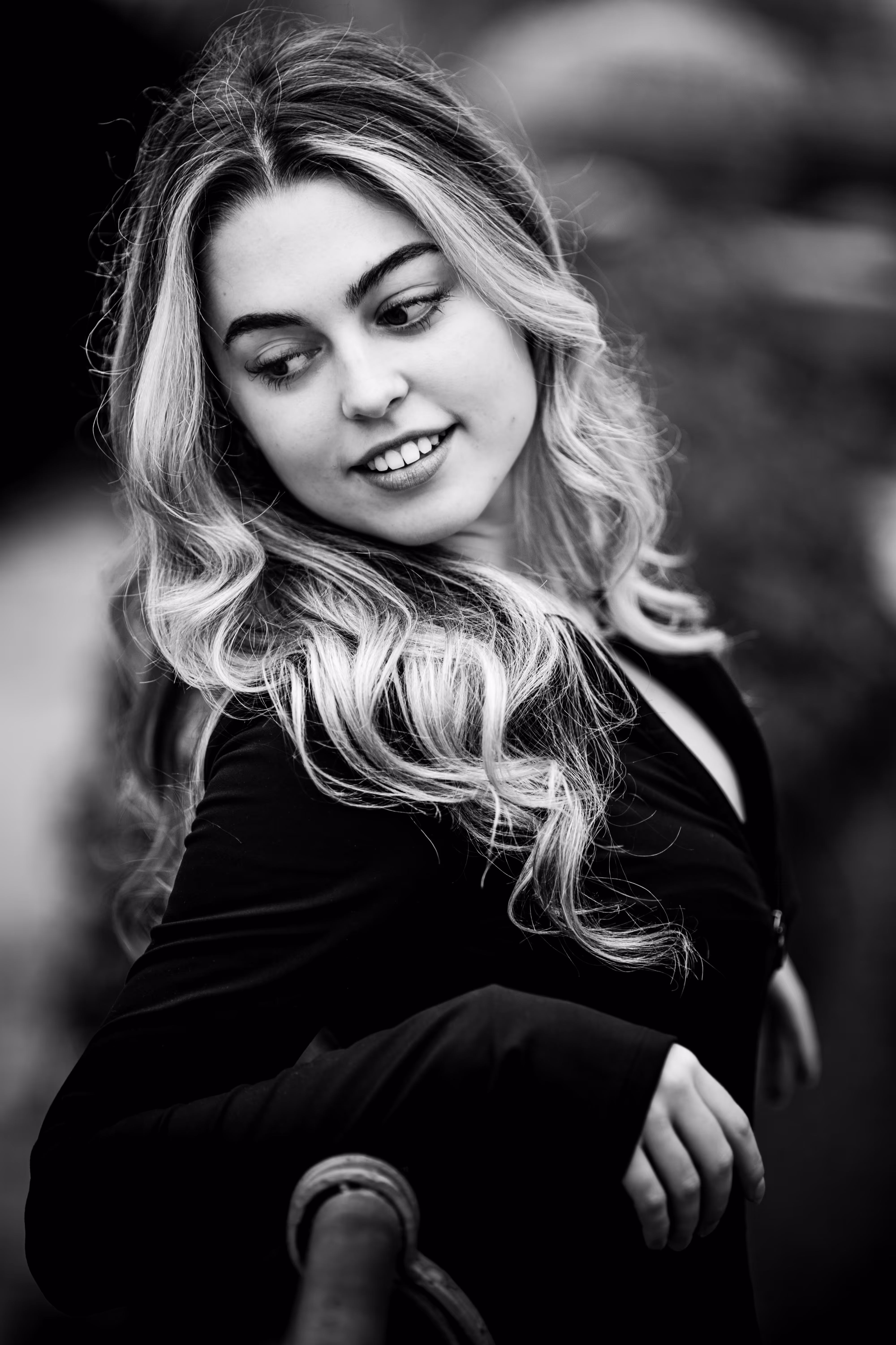 Stimmungsvolles Schwarz-Weiß-Porträt von Model Valentina mit langen blonden Locken, die mit einem leichten Lächeln nach unten zur Seite blickt