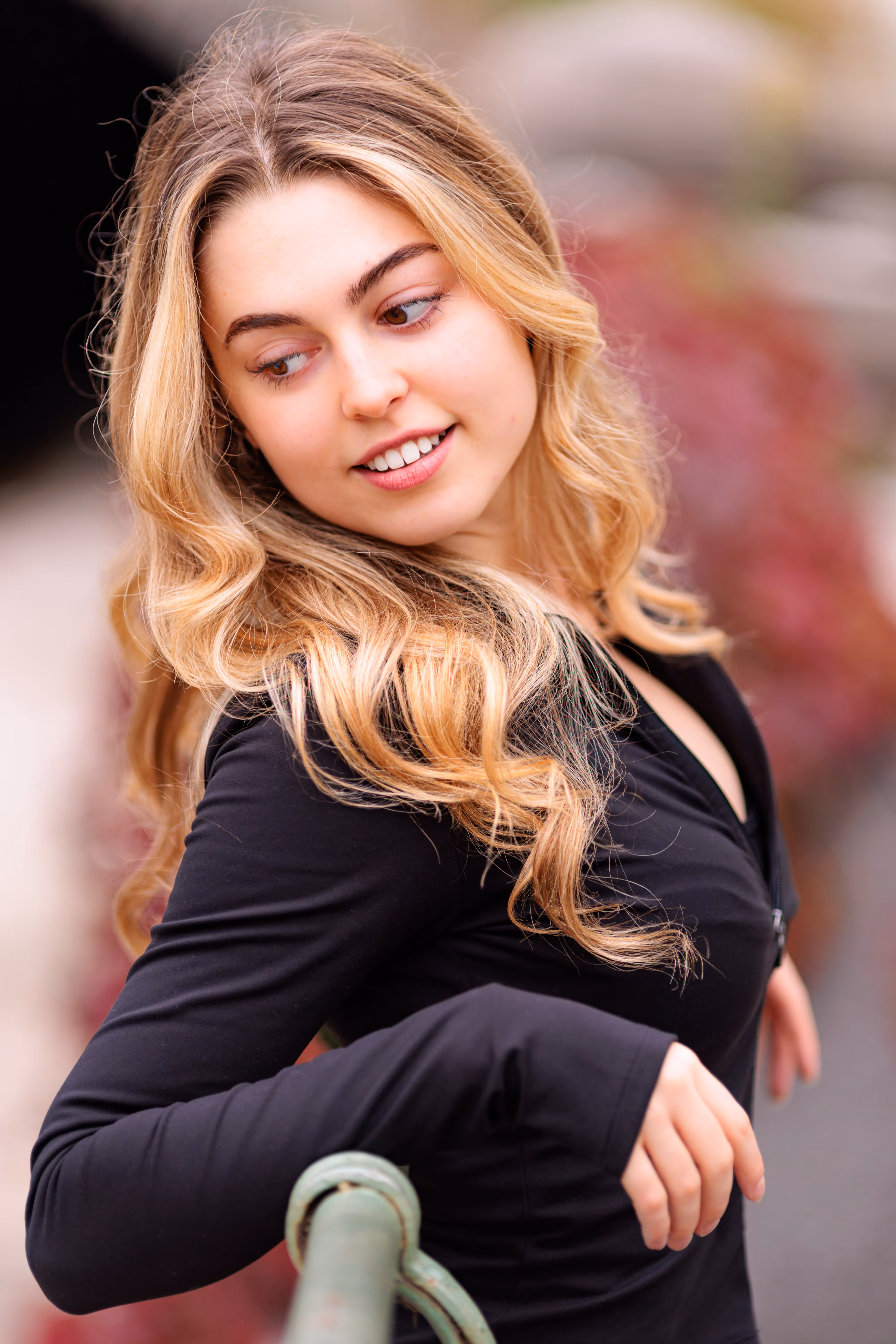 Model Valentina mit langen, blonden Locken blickt bei einem Porträt-Shooting im Wiener Stadtpark lächelnd zur Seite