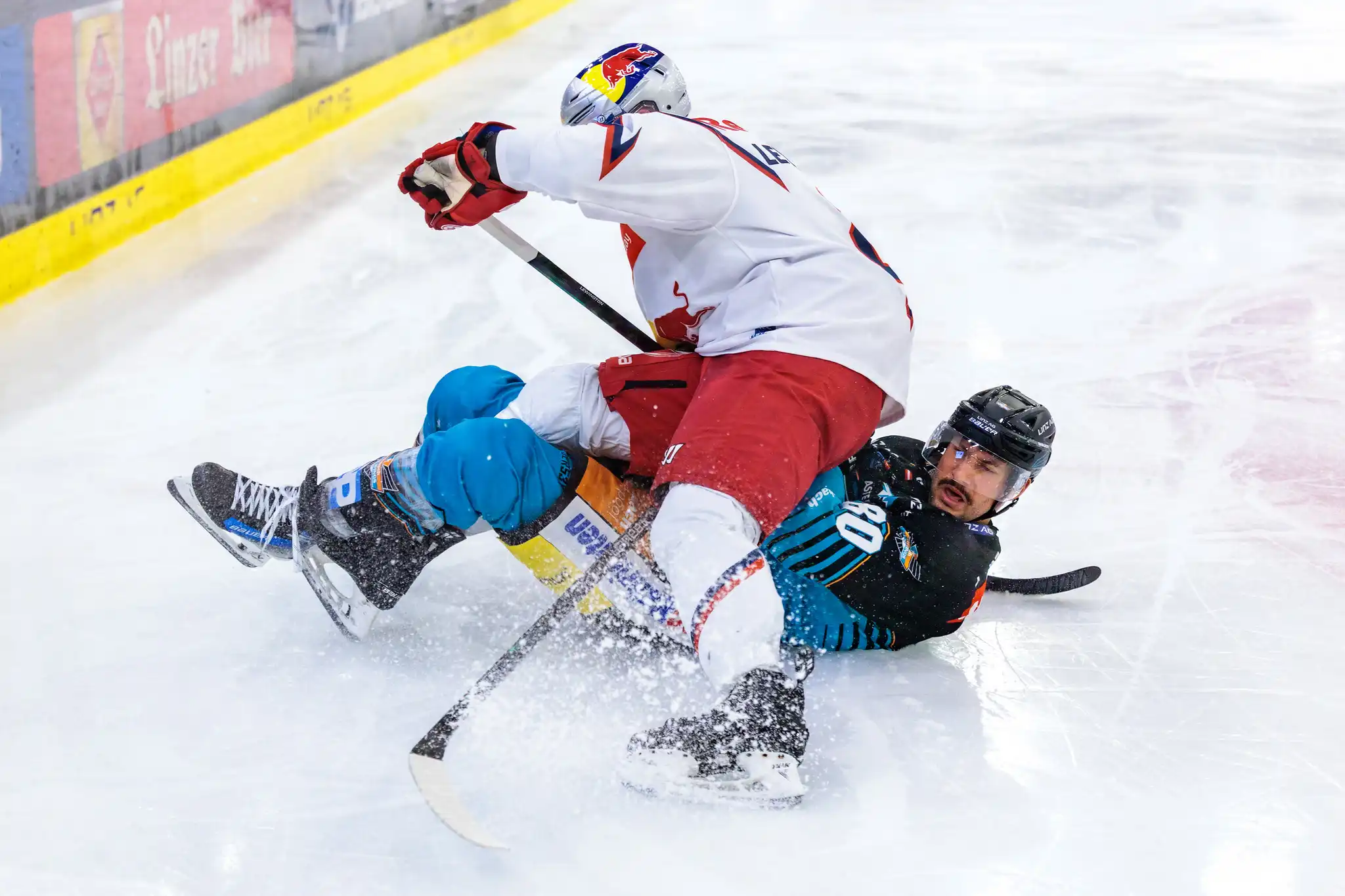 Julian Pusnik von den Steinbach Black Wings Linz wird im intensiven Eishockey-Zweikampf von Tyler Lewington vom EC Red Bull Salzburg zu Boden gerungen