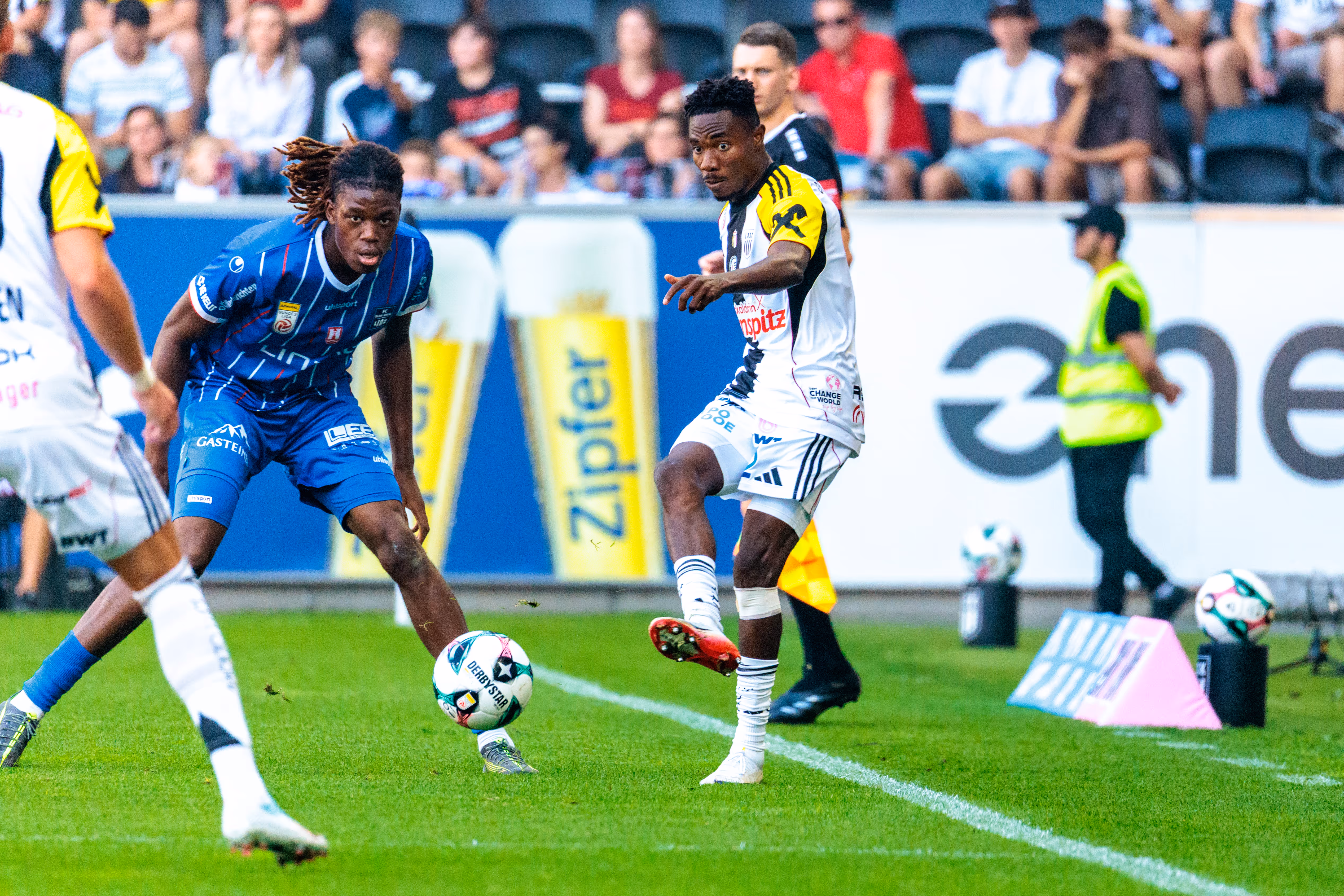 Elias Bakatukanda vom FC Blau-Weiß Linz bedrängt LASK-Spieler Moses Usor in einem intensiven Zweikampf um den Ball während des Linzer Derbys
