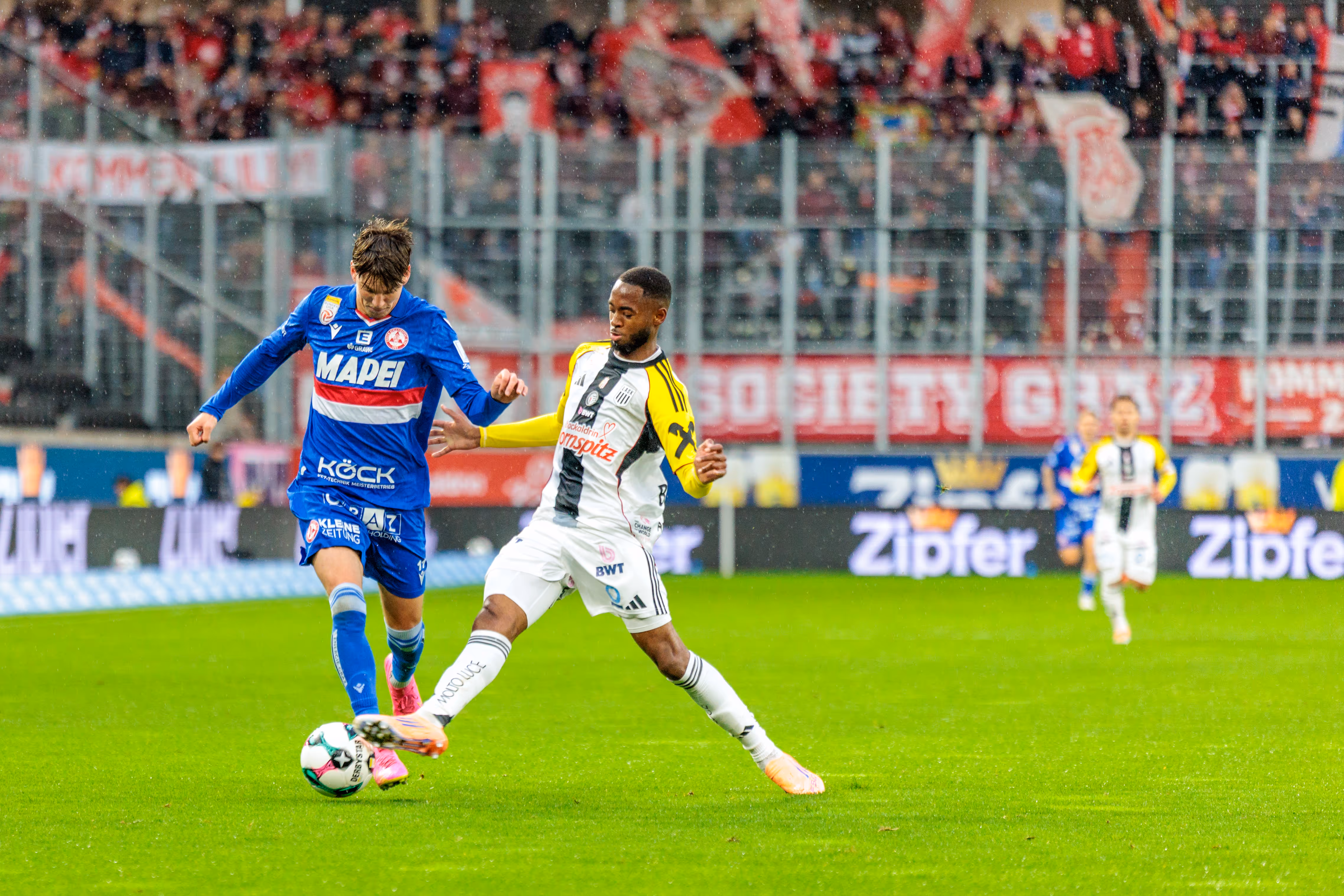 GAK-Spieler Tio Cipot führt den Ball am Fuß und wird im intensiven Zweikampf von einem Verteidiger des LASK attackiert