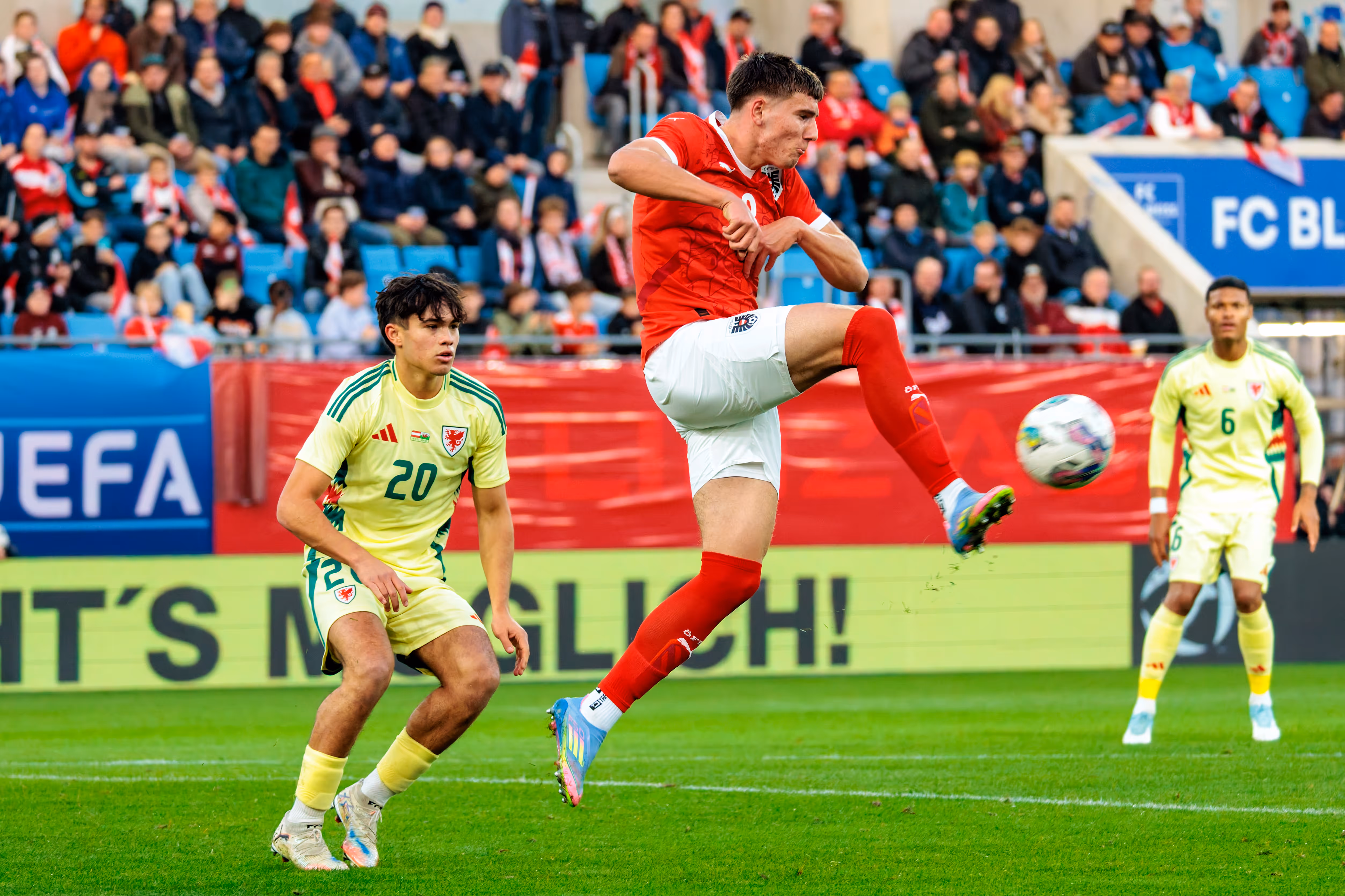 Der österreichische U21-Spieler David Piczka schießt den Ball in einem dynamischen Sprung, während der walisische Gegenspieler Gabriele Biancheri die Aktion beobachtet